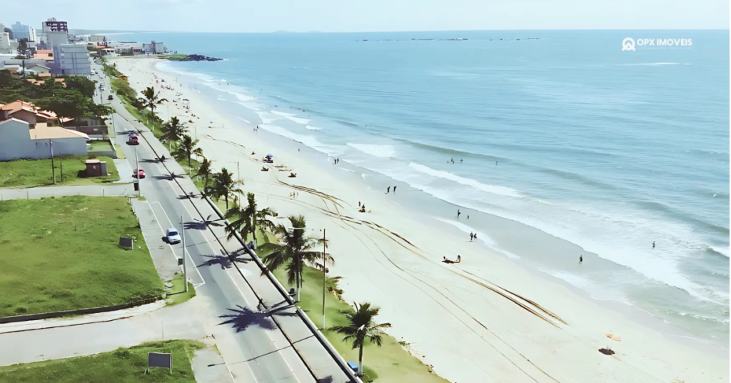 Imagem da Praia do Tabuleiro em SC mostrando a orla urbanizada, mar azul e potencial imobiliário da região, destacando-se no mercado de luxo em Santa Catarina.